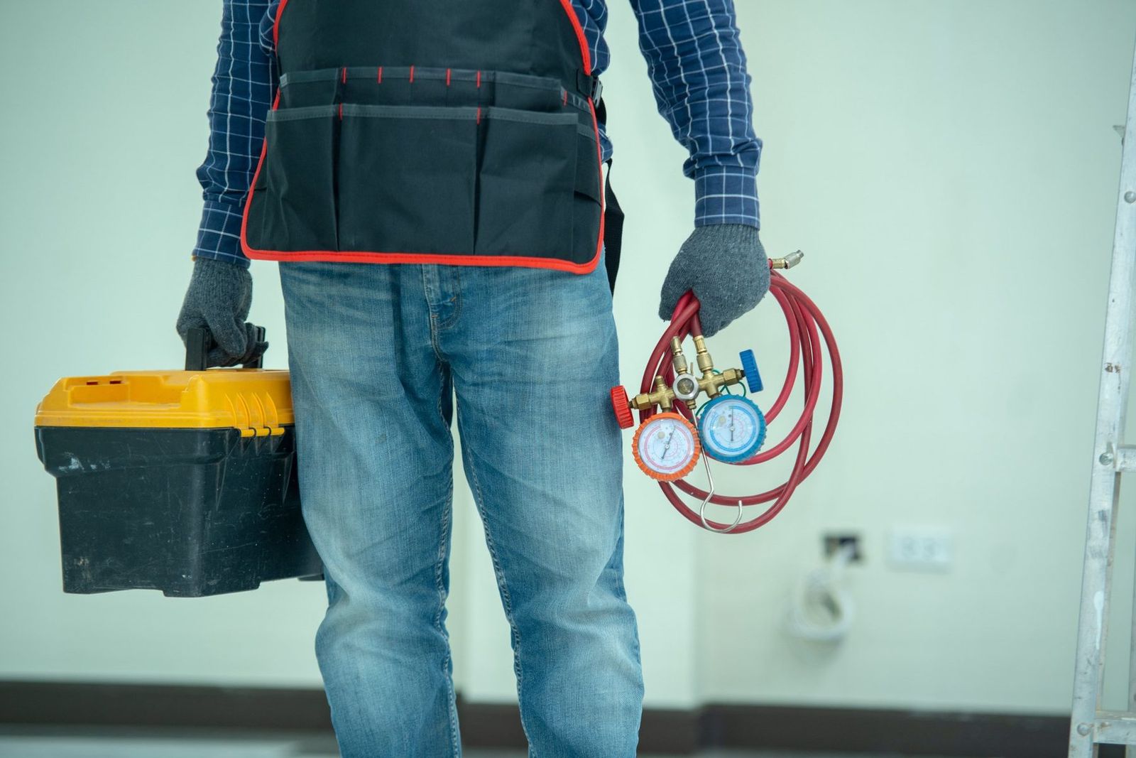 HVAC technician with gauges and tool bag